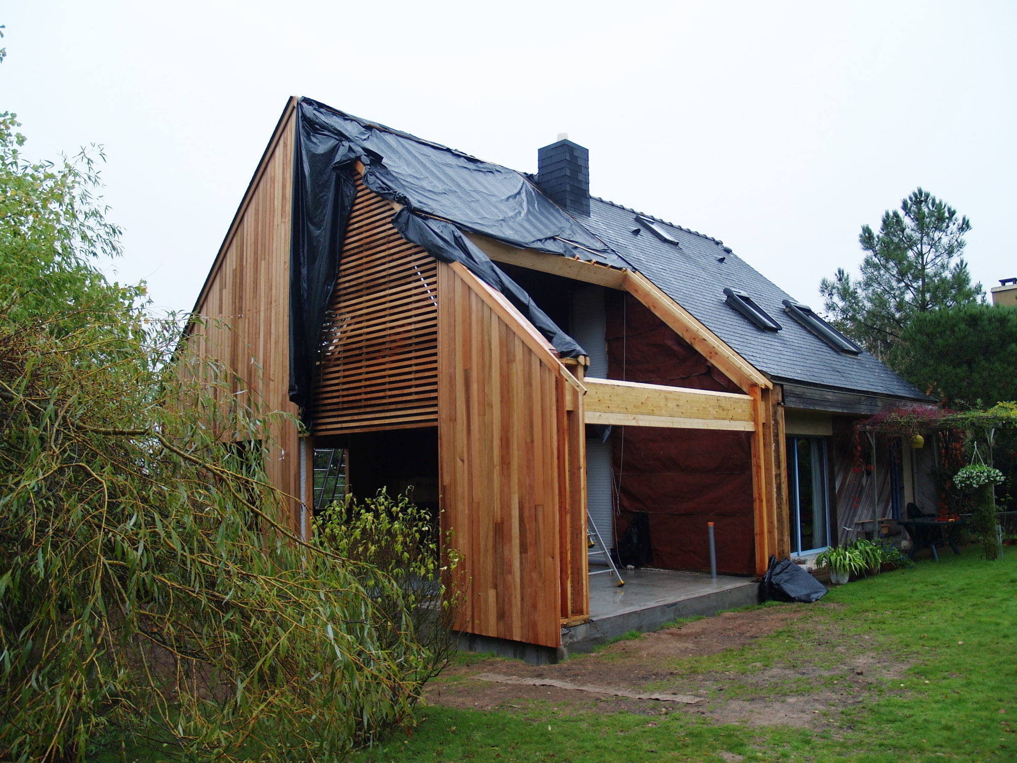 Extension de maison en cours avec échafaudages et plans architecturaux